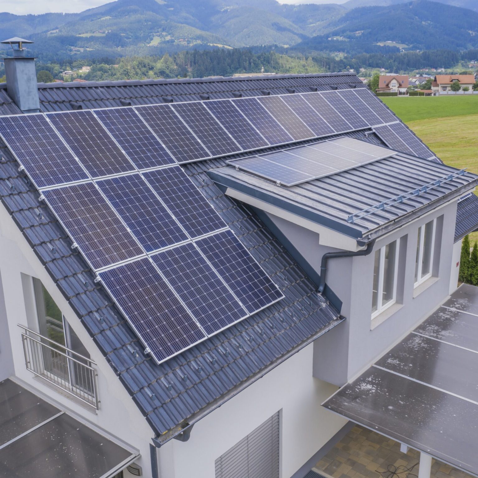 A high angle shot of a private house situated in a valley with solar panels on the roof